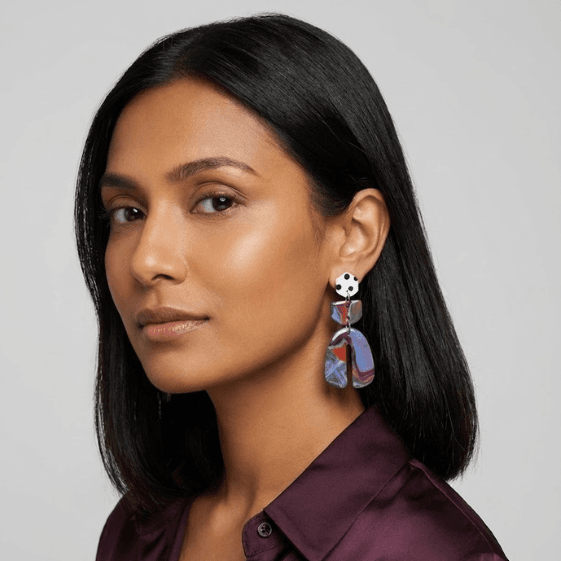 Model wearing horseshoe earrings with a white black polka dot stud, marbled connector in red-blue tones, and a marbled horseshoe-shaped drop in purple, blue, and red.