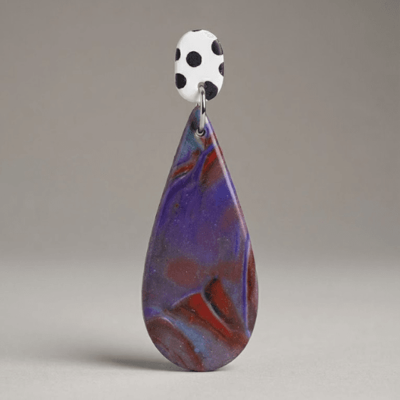 Close-up of fimo earrings with a white black polka dot stud and a purple-blue-red marbled teardrop drop on a light grey background.