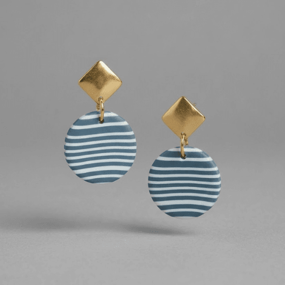 flat lay of handcrafted polymer clay hanging earrings with gold geometric studs and striped drops, part of blueberry bloom handcrafted jewelry collection