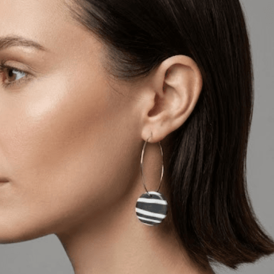 woman wearing zebra print polymer clay hoop earrings with stainless steel hoops, photographed close-up for blueberry bloom jewelry collection
