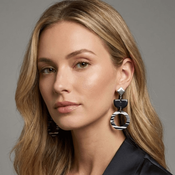 close-up of handmade fimo jewelry featuring black and white geometric drop earrings with striped ring design, worn by a woman for blueberry bloom