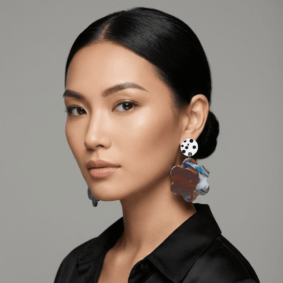 Model wearing floral earrings with a white black polka dot stud and a multicolor marbled flower-shaped drop (red, blue, green, and white).