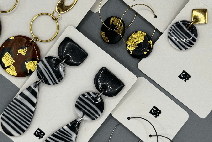 close-up of handmade zebra print hoop earrings with polymer clay charms on stainless steel hoops, displayed on white blueberry bloom cards