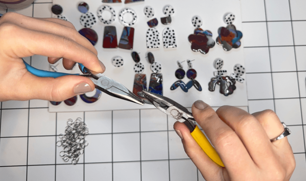 Making handmade Fimo polymer clay earrings by hand — shaping and assembling pieces at the worktable.