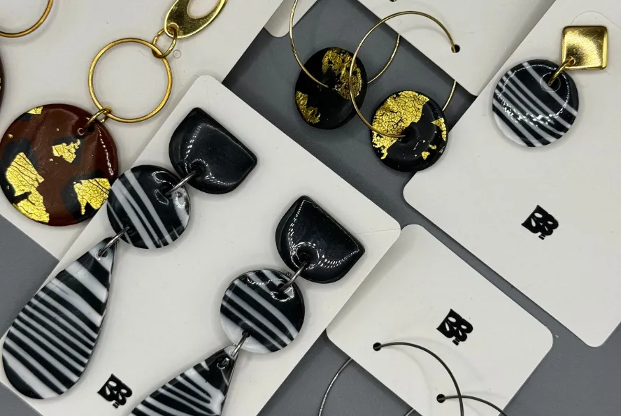 close-up of handmade zebra print hoop earrings with polymer clay charms on stainless steel hoops, displayed on white blueberry bloom cards