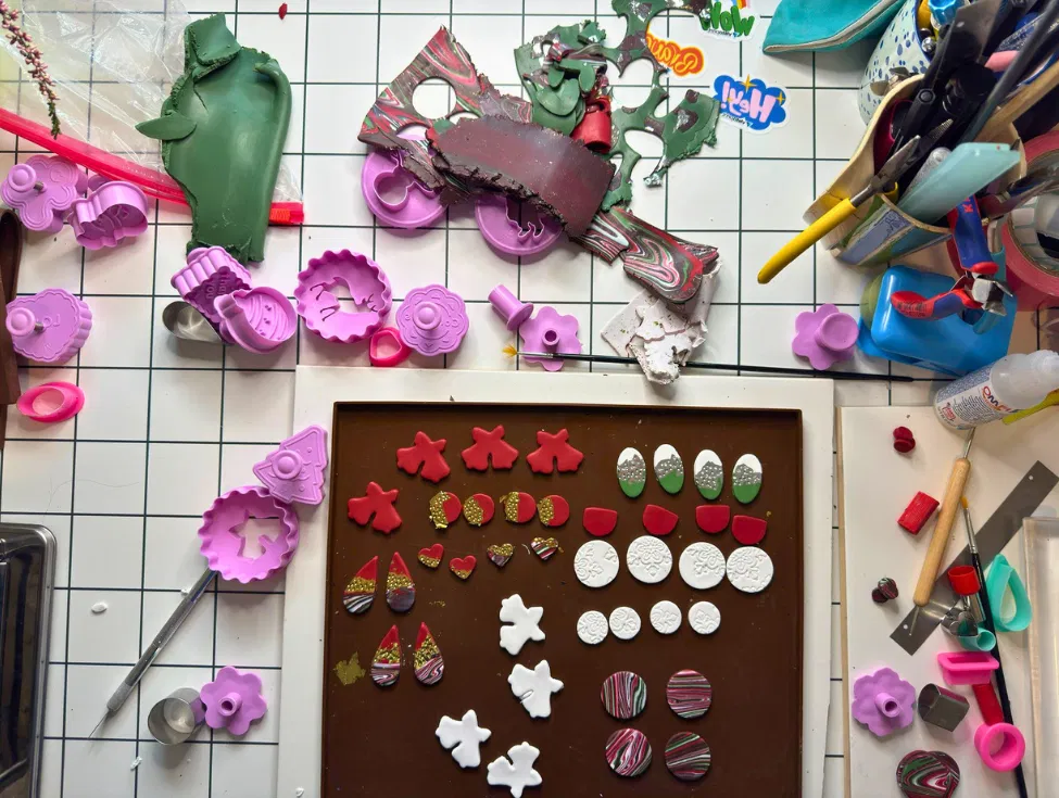 Handmade DIY Christmas earrings in red, white, green, and gold displayed on cards, ready for a Christmas market.