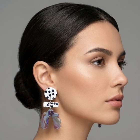 Model trägt Polka-Dot-Ohrringe mit rundem schwarz-weiß gepunktetem Stecker, passendem gepunktetem Stab-Verbinder und marmoriertem, gewellten Bogen-Anhänger in lila-grünen Tönen.